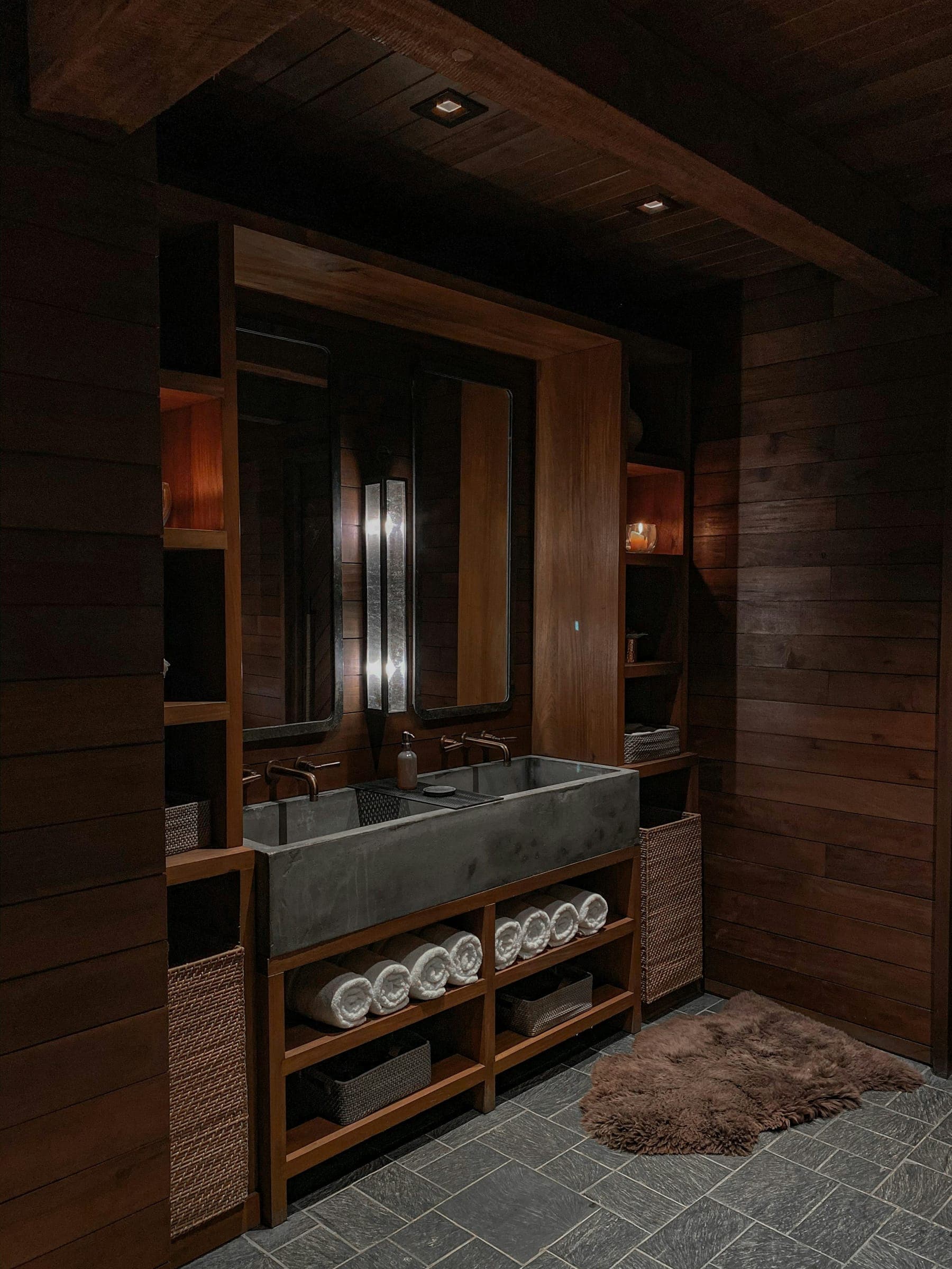 Concrete trough sink with wall-mounted taps, framed by dark wood shelving