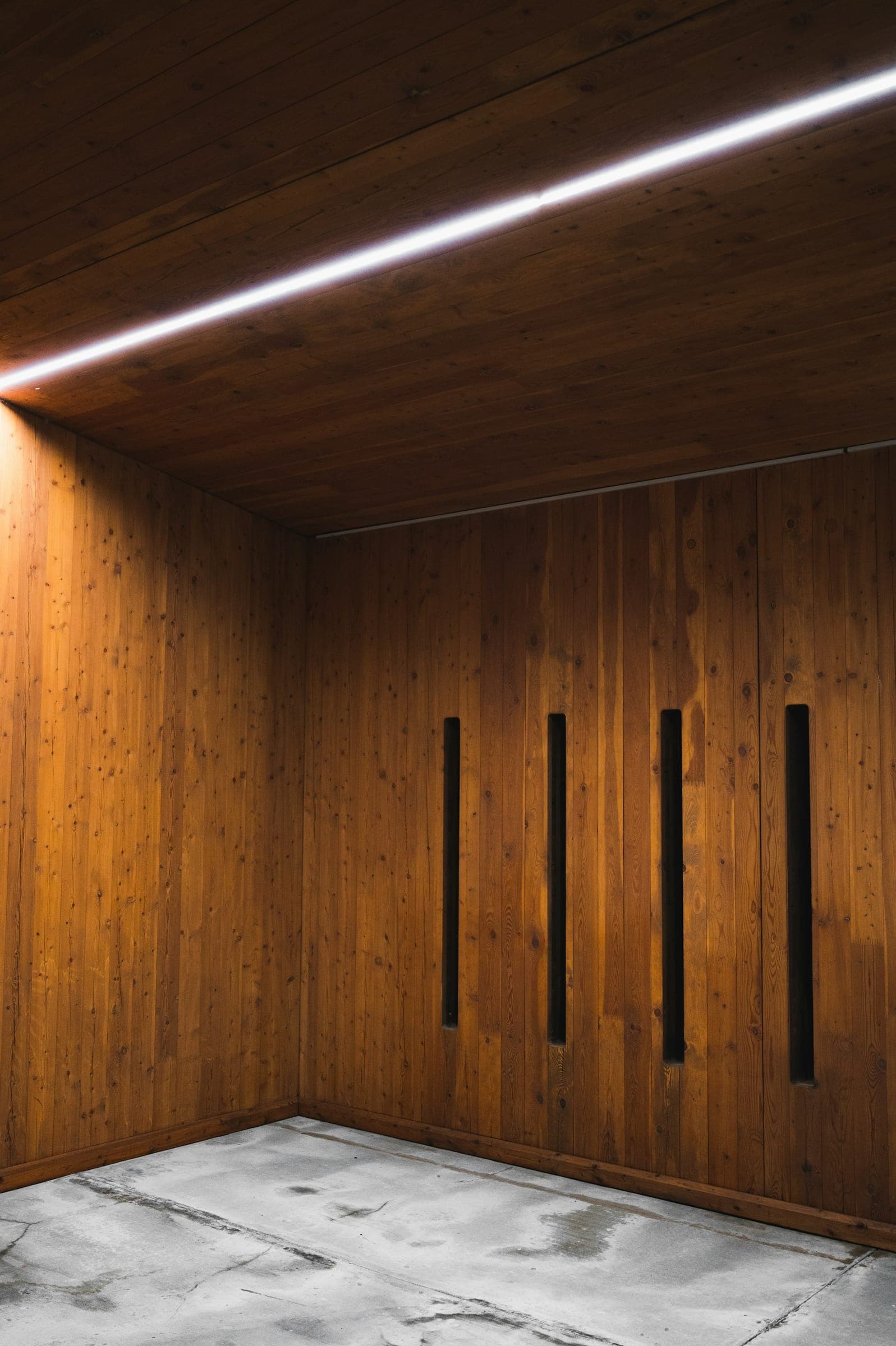 Room lined floor to ceiling in warm wood panels with slim recessed pulls