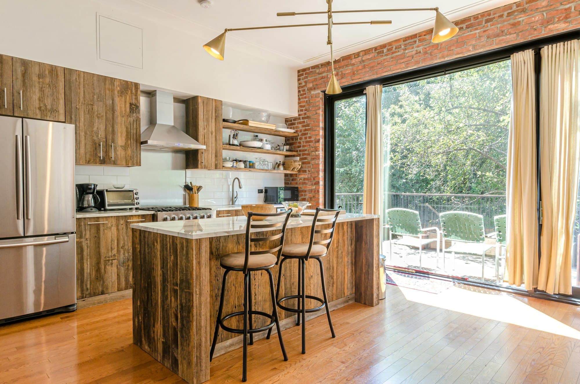 Kitchen with a walnut island, pale cabinetry and pendant lights
