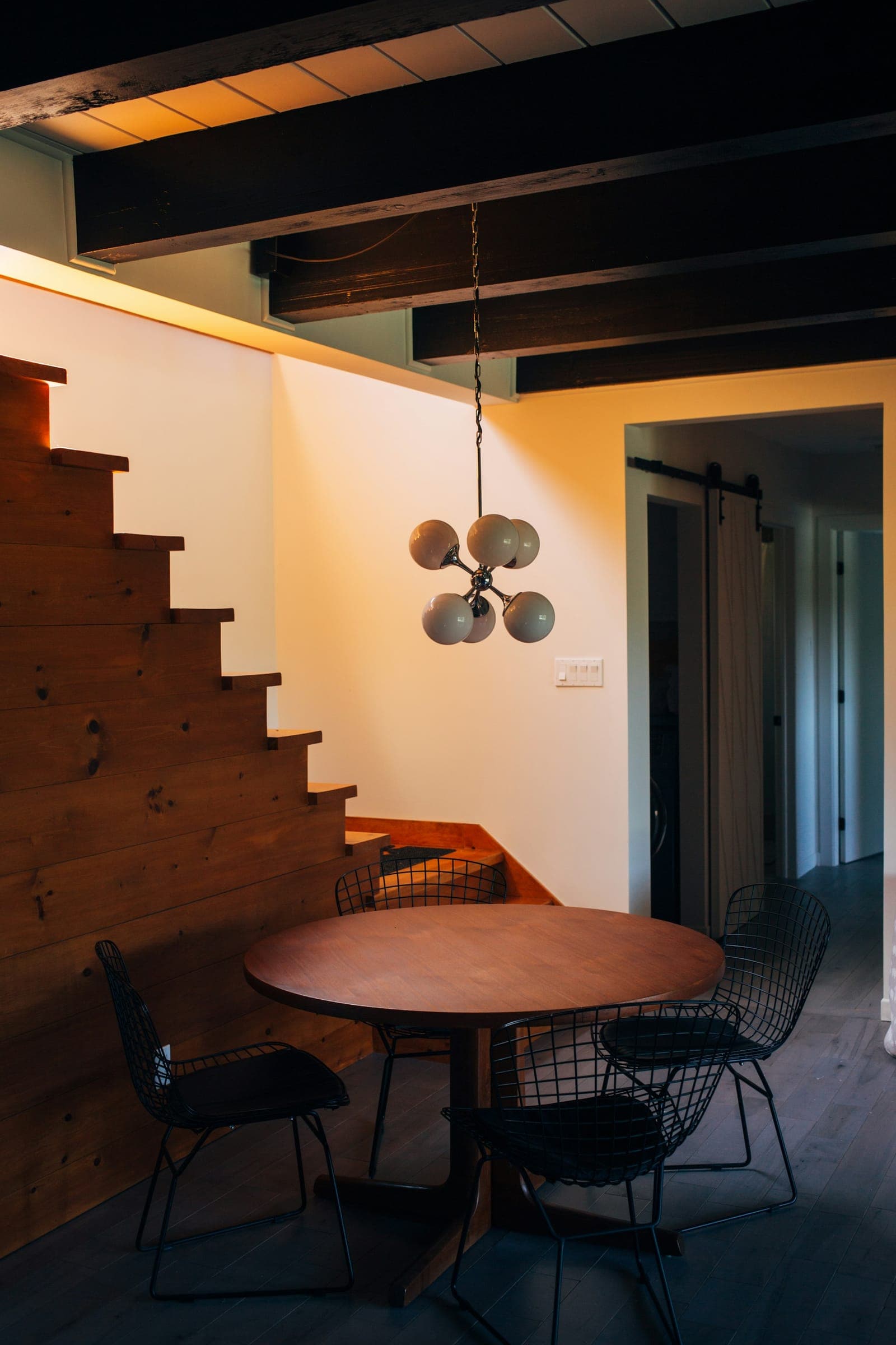 Wood stair with a round table and globe pendant tucked beside it